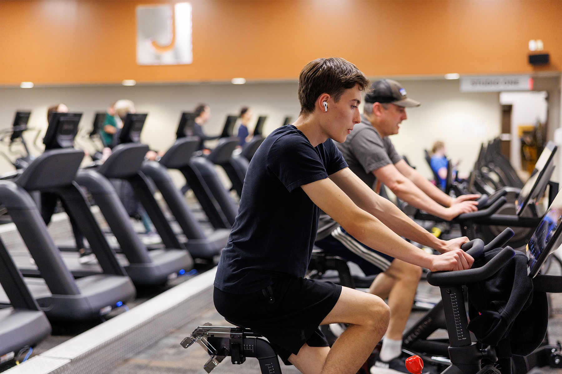 A JCC Buffalo trainer supports a member pushing a weighted exercise sled